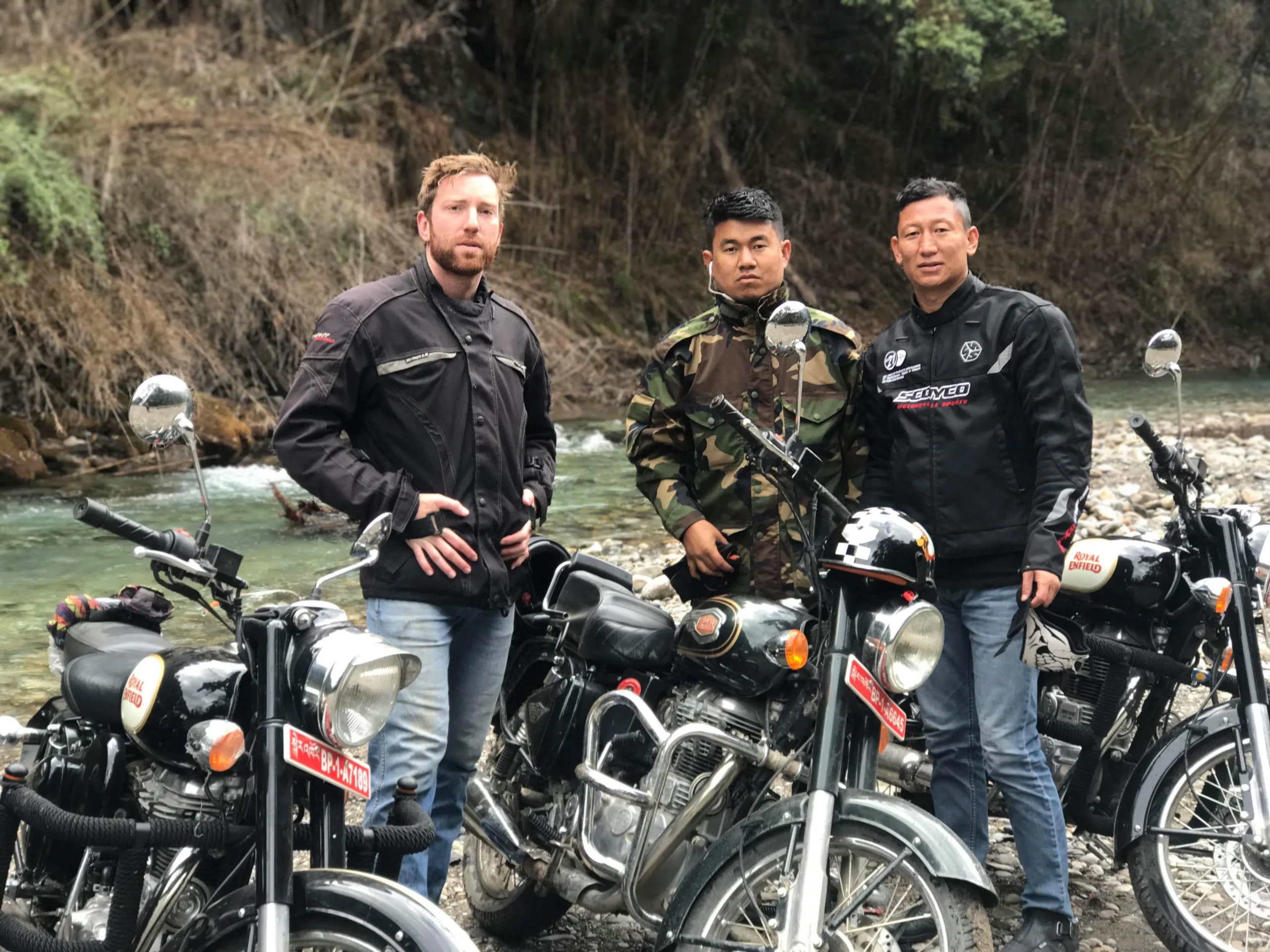 Motorbike riders crossing a mountain stream in Bhutan on a bike tour.